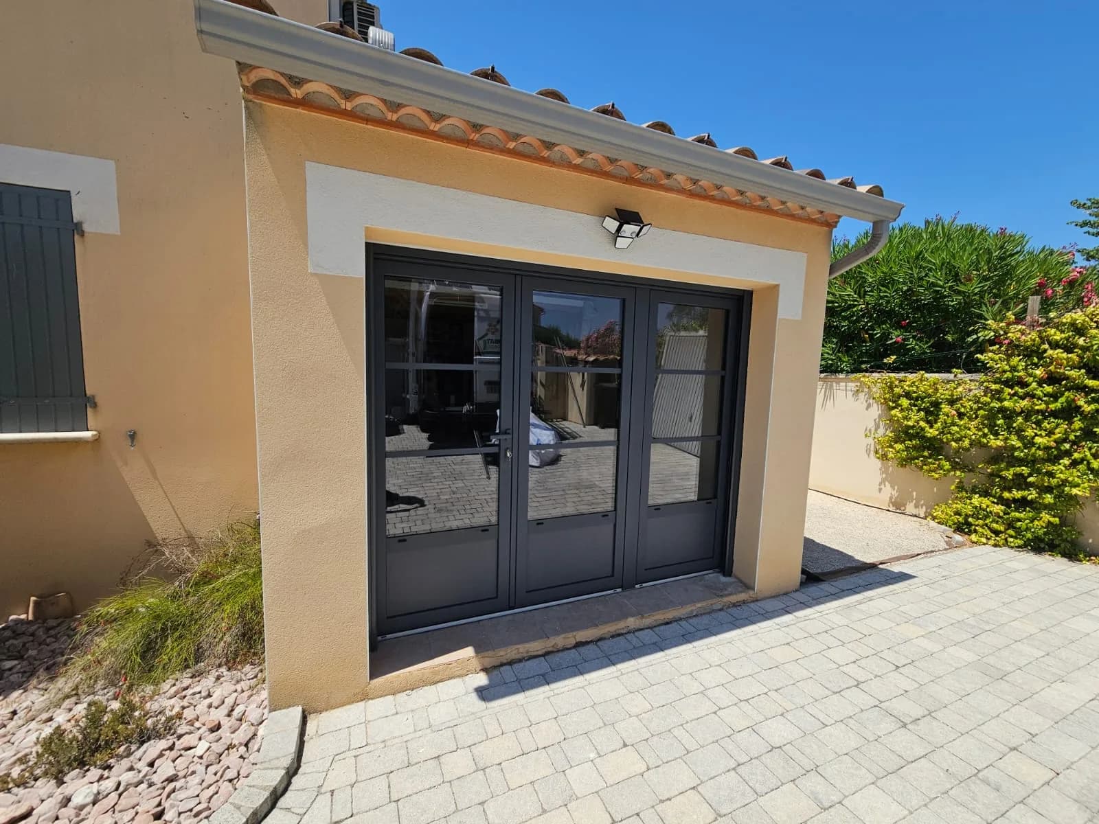 Nouvelle baie vitrée noire avec volet roulant, façade maison Garrigues Sainte Eulalie.