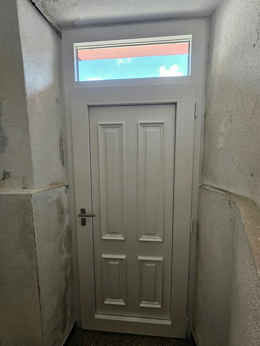 Intérieur d'une porte d'entrée PVC blanche avec imposte vitrée et panneau isolant à Fons.
