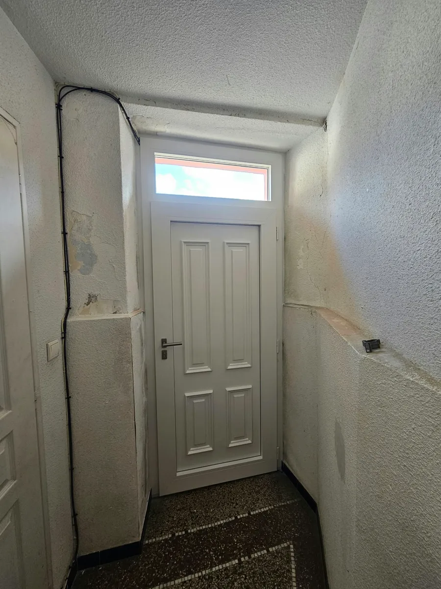 Extérieur d'une porte d'entrée PVC blanche tiercée avec imposte et numéro 4 à Fons.