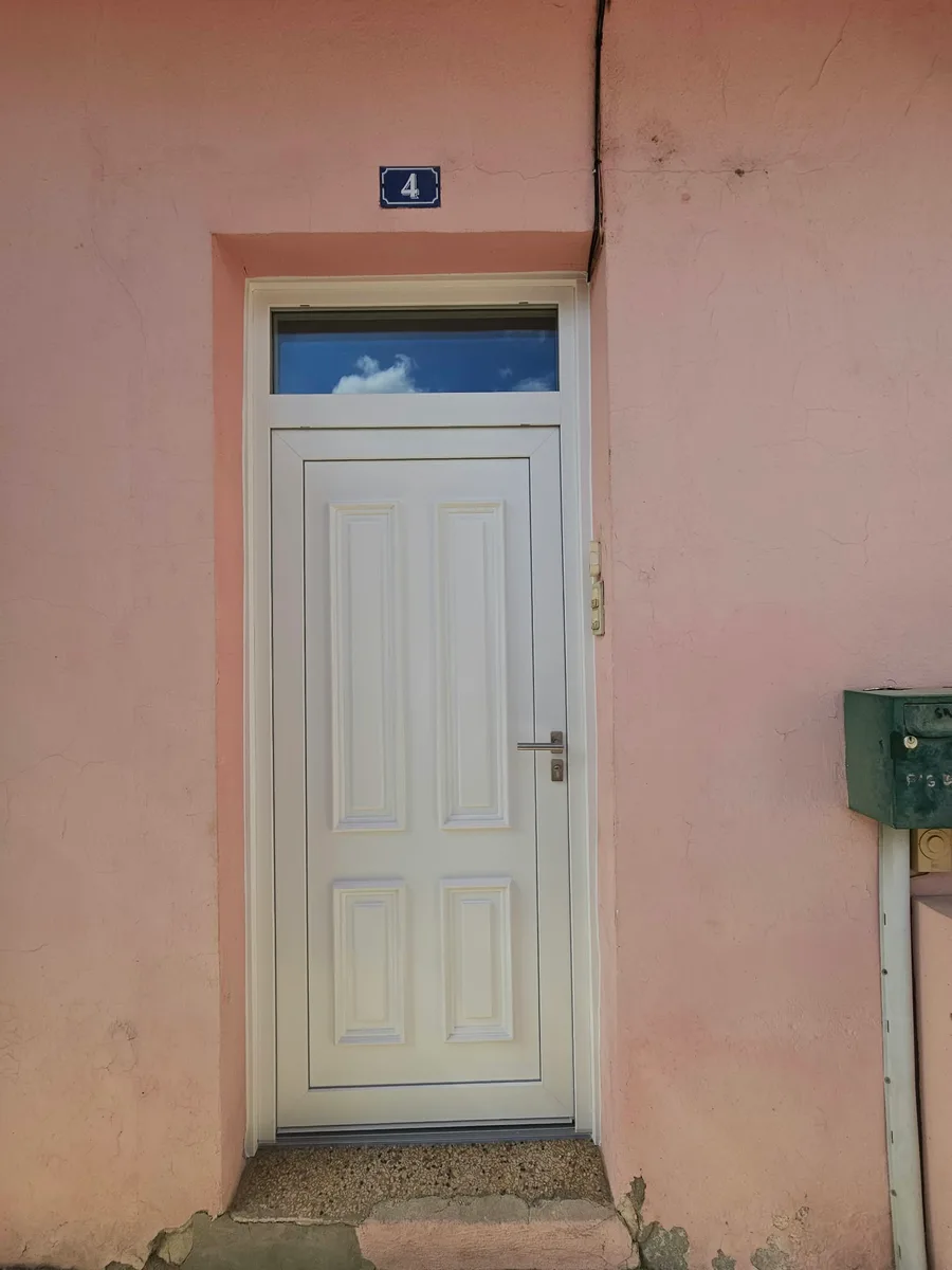 Intérieur d'une porte d'entrée PVC blanche standard installée à Fons.