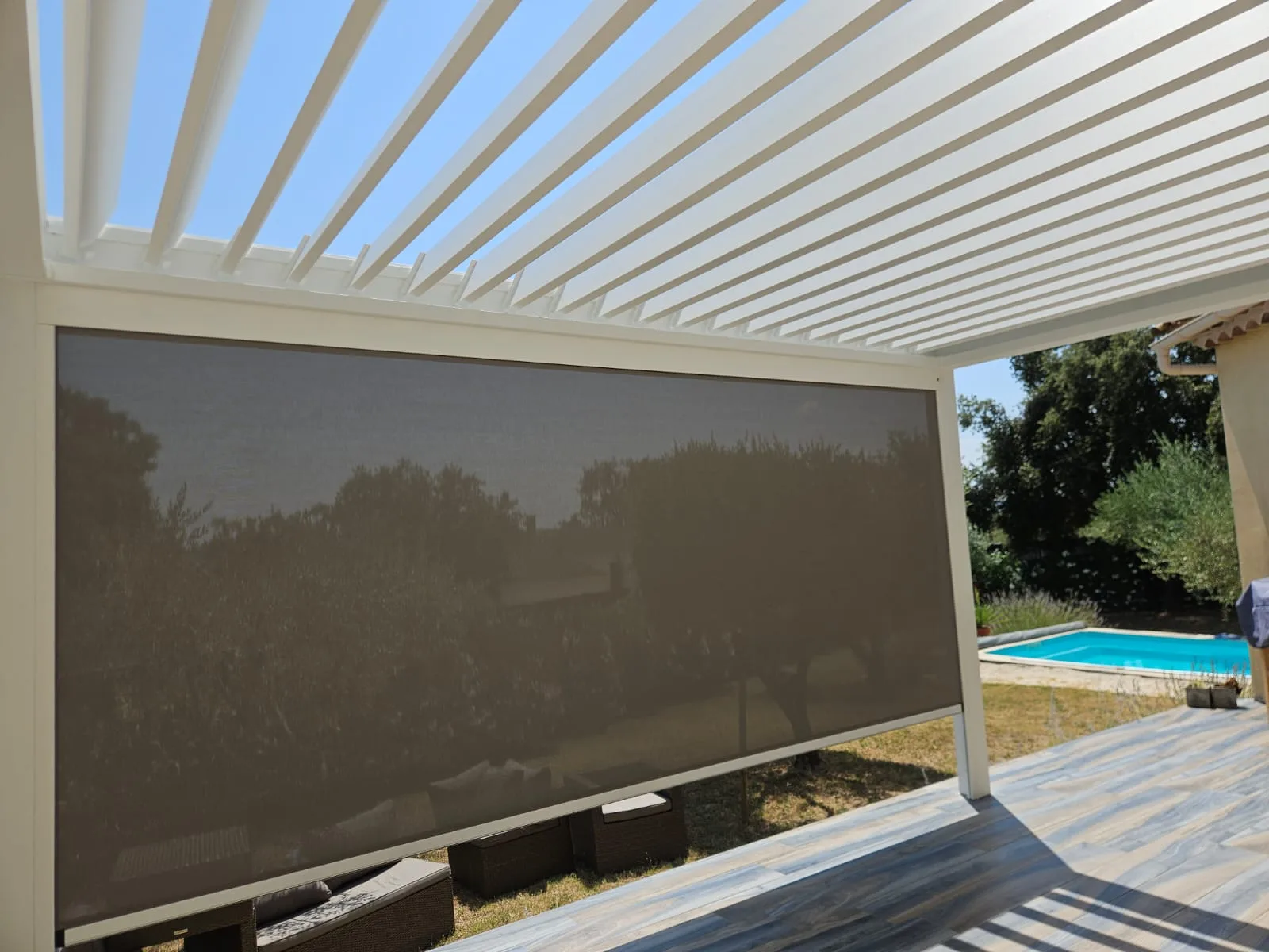 Screen occultant déroulé sous les lames ouvertes de la pergola Brustor