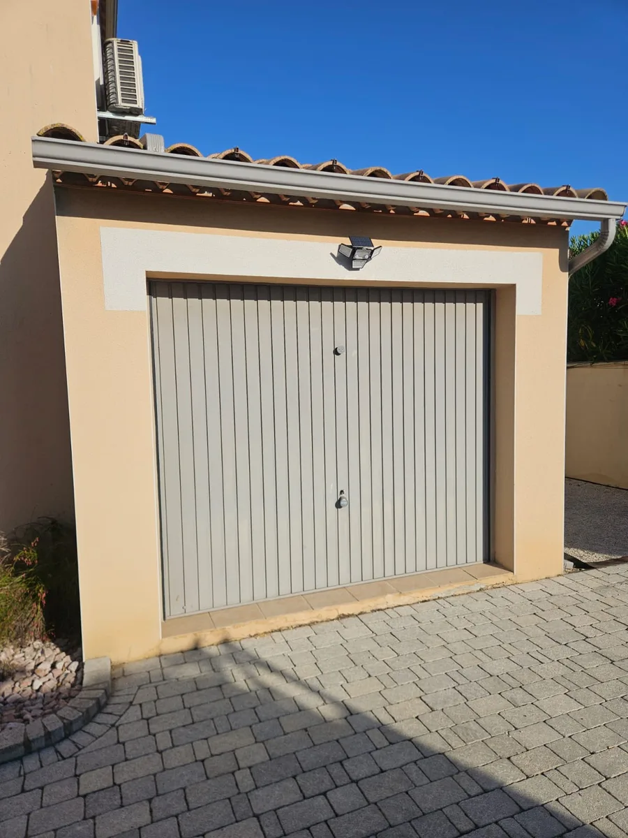 Ancienne porte de garage grise, extérieur maison à Garrigues Sainte Eulalie.