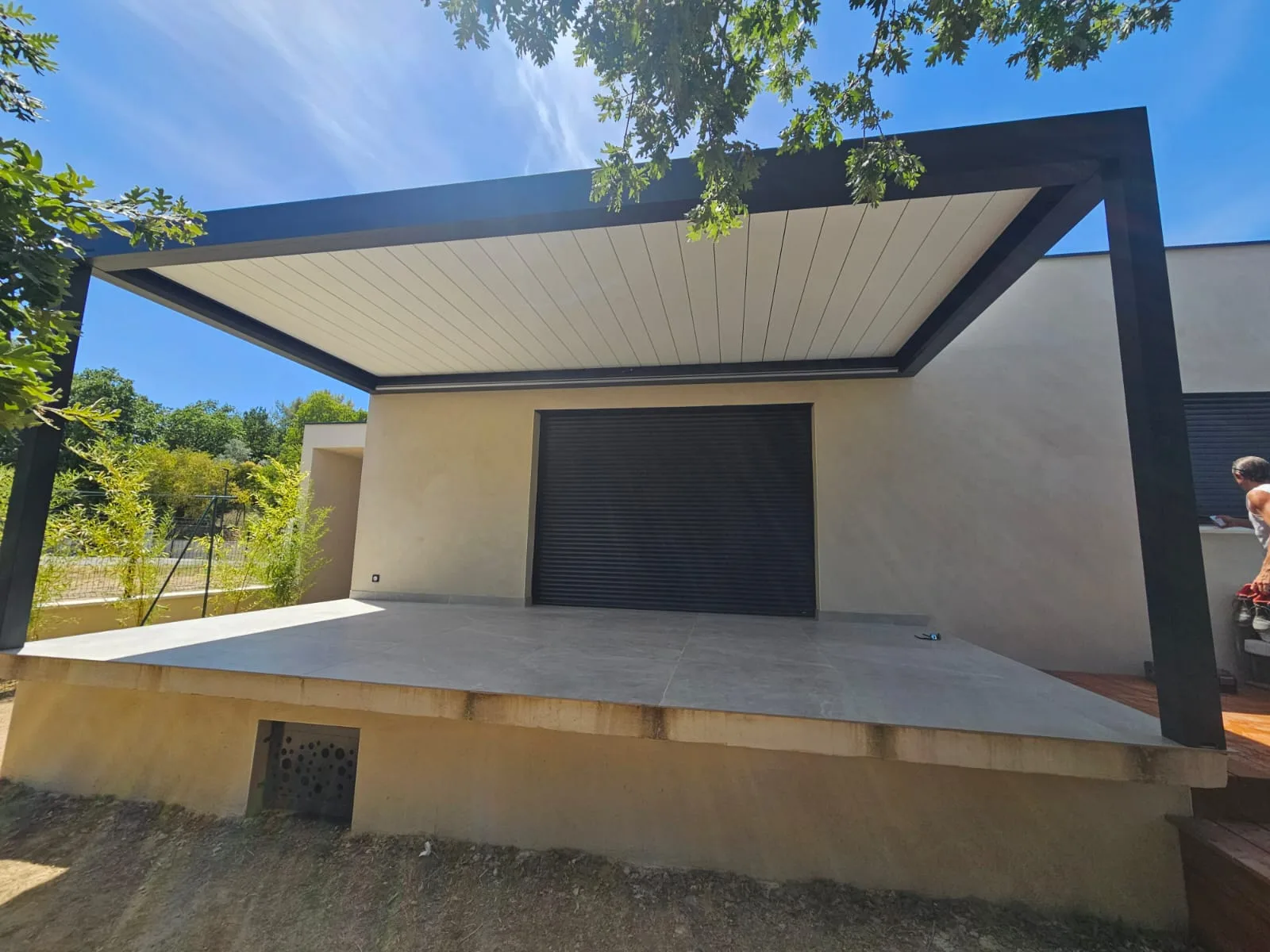 Lames orientables blanches de la pergola Brustor avec vue sur la piscine et le jardin.