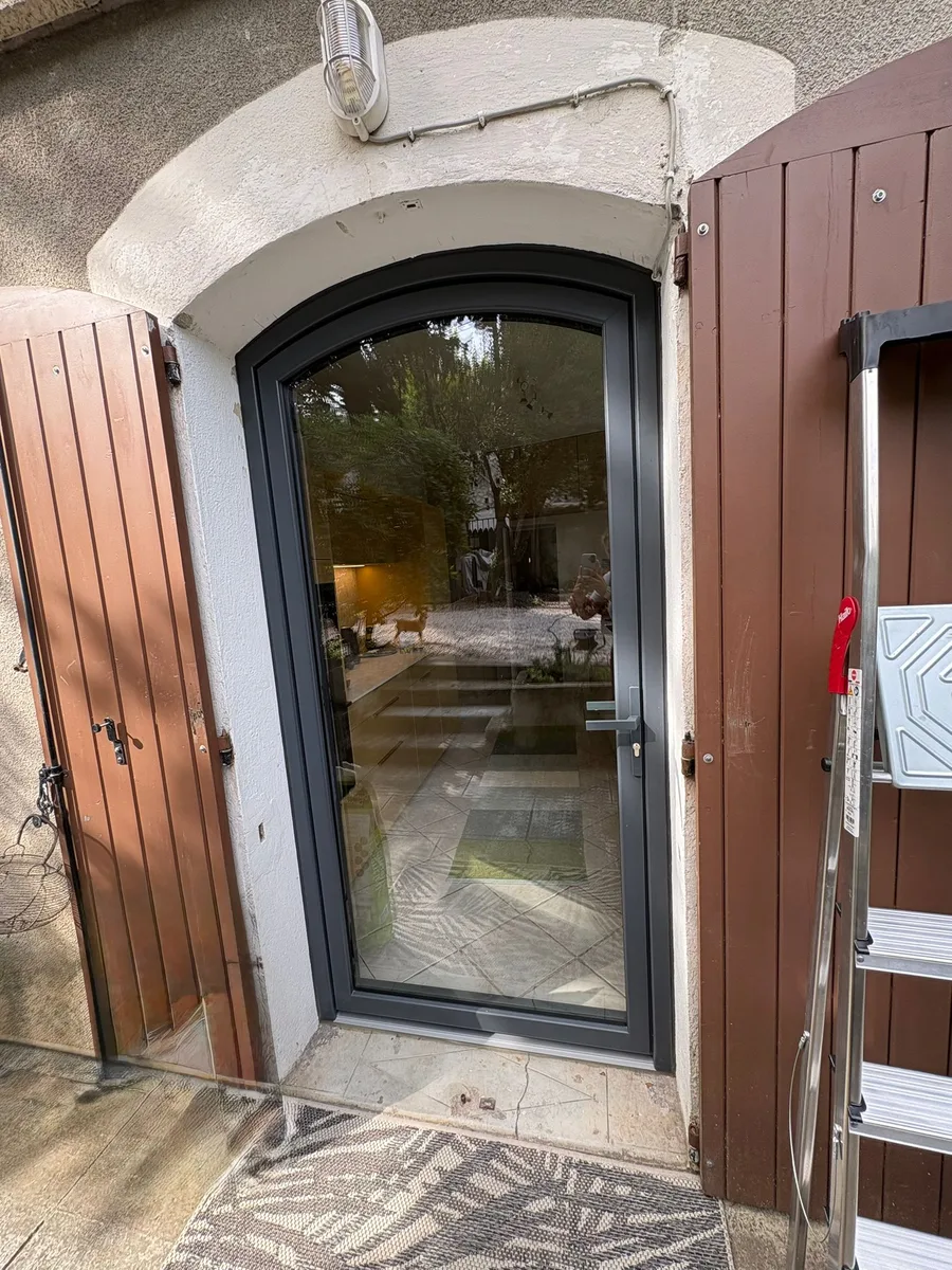 Porte d'entrée vitrée cintrée PVC gris anthracite, vue extérieure, volets bois, Nîmes.