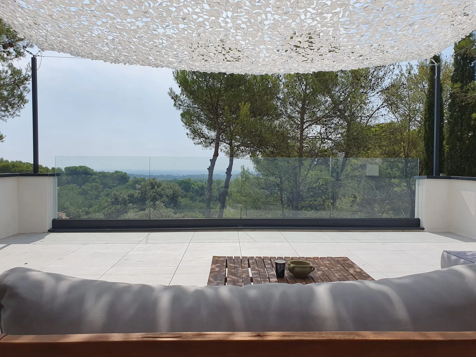 Vue depuis le canapé sur garde-corps en verre et paysage à Nîmes.