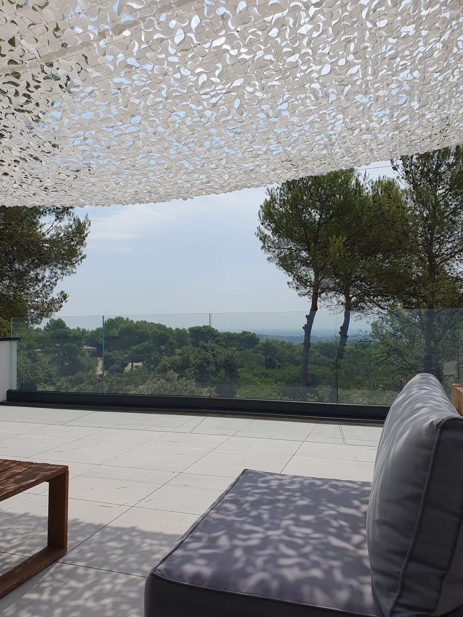 Terrasse moderne avec table, canapé, et garde-corps transparent à Nîmes.