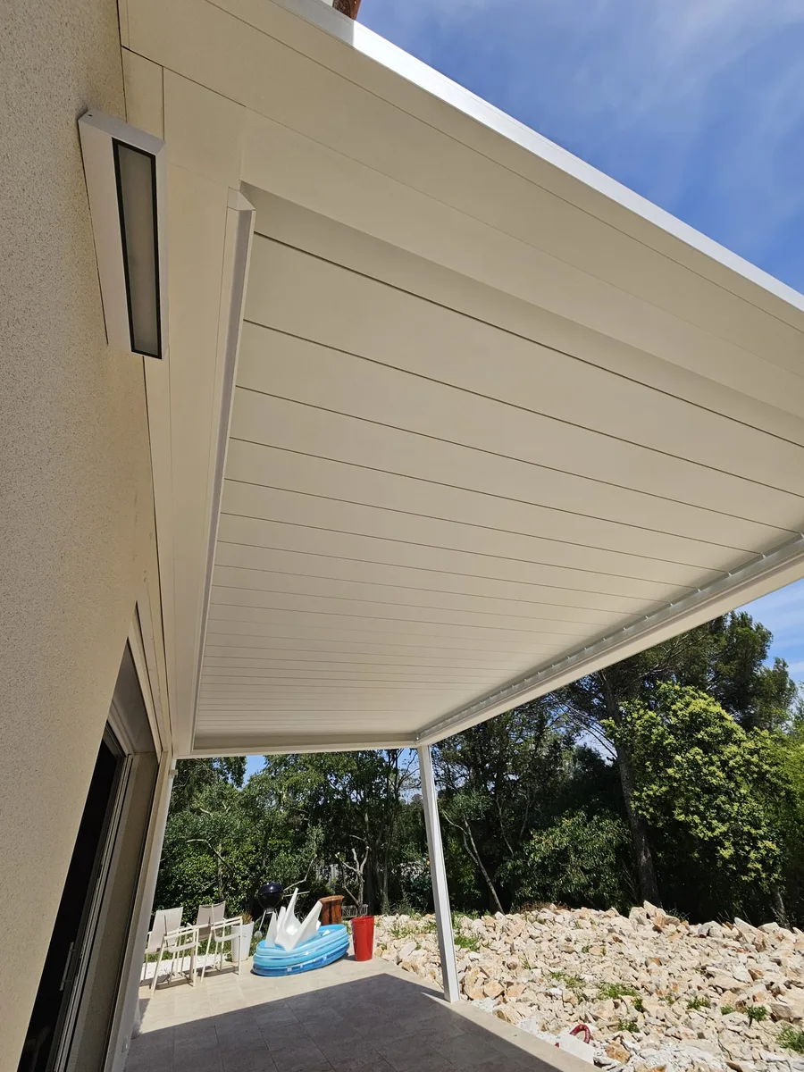 Vue latérale de la pergola Brustor avec lames ouvertes et screen intégré sur une terrasse.