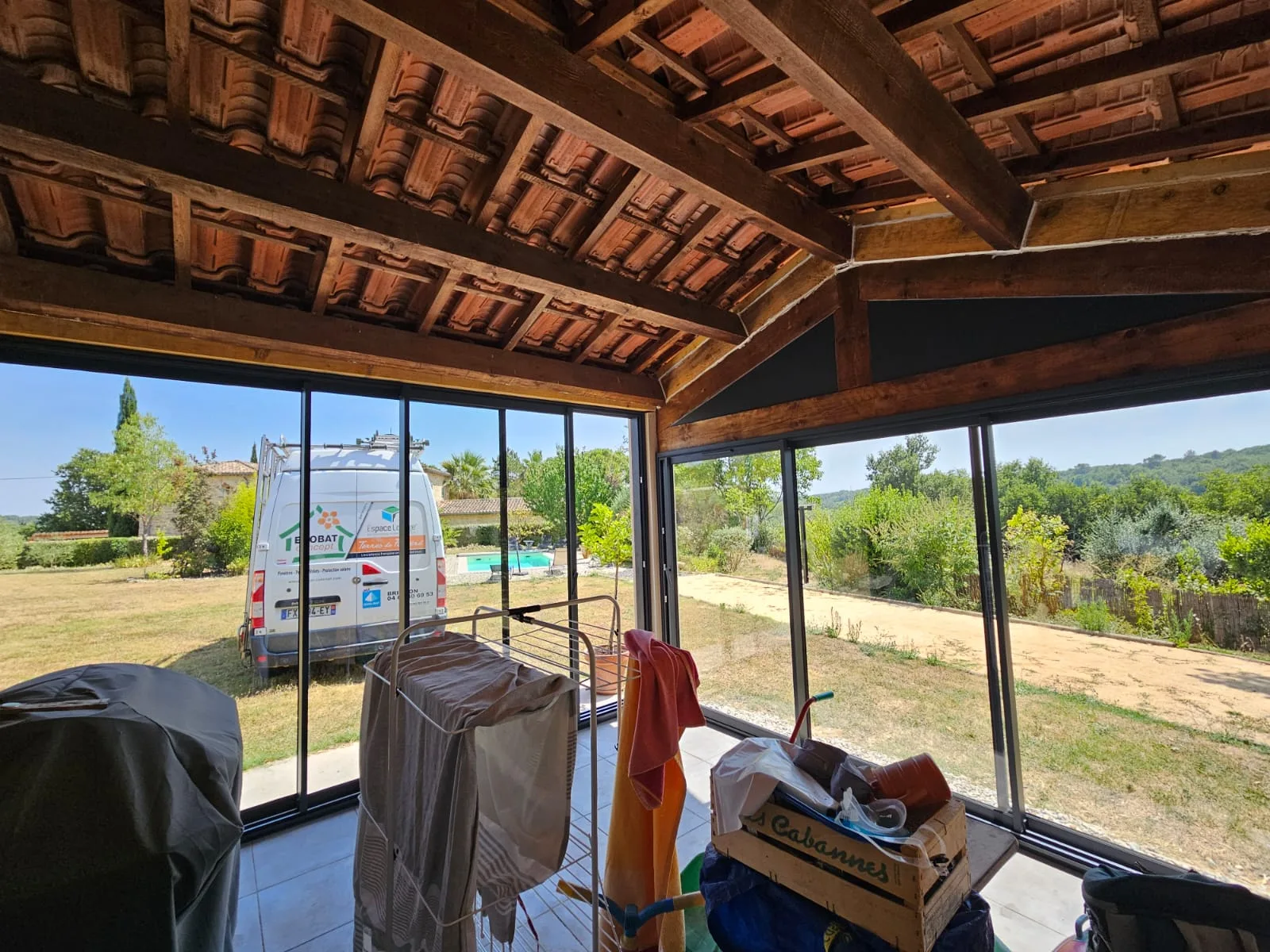 Intérieur de la véranda avec vue sur le jardin et la piscine depuis Saint-Cézaire-de-Gauzignan.