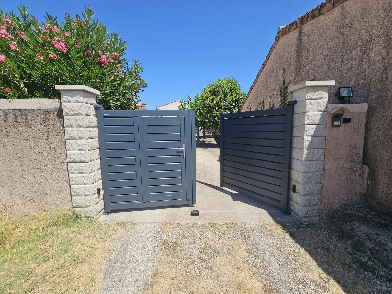 Vue intérieure d'un portail aluminium gris foncé ouvert sur une allée à Saint Chaptes.