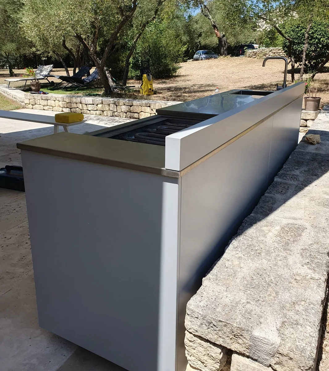 Vue latérale d'une cuisine extérieure sur mesure avec grill encastré, installée à Sommieres.