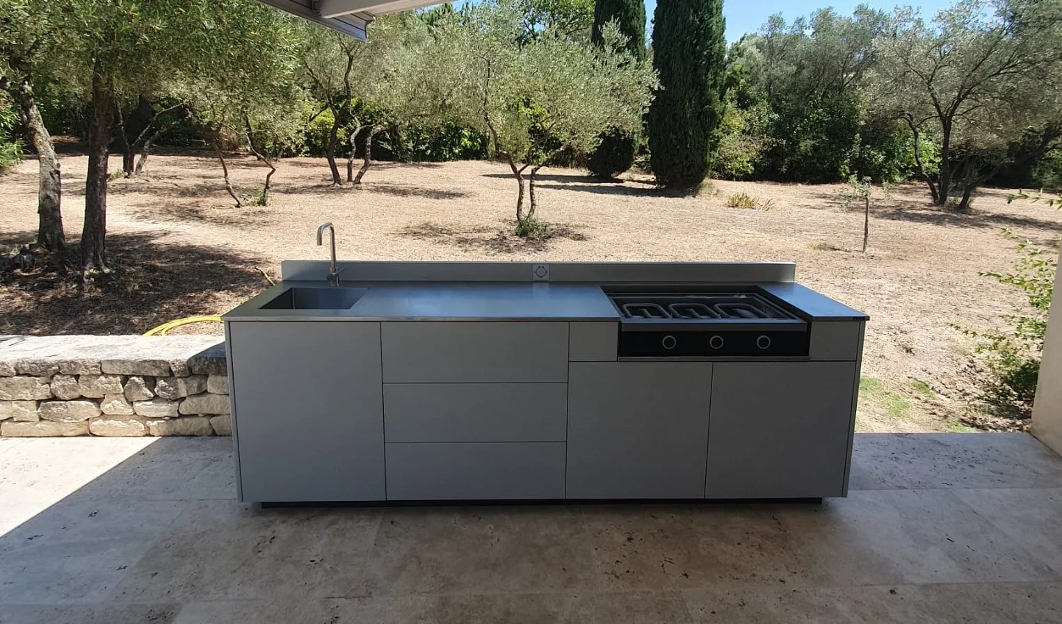 Cuisine extérieure complète en gris clair sur une terrasse en pierre à Sommieres, Gard.